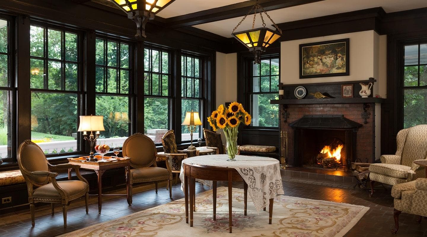 Cozy living room with large windows, a fireplace, and a table adorned with sunflowers.