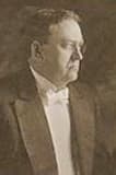 A formal portrait of a middle-aged man wearing a tuxedo, looking to the side.