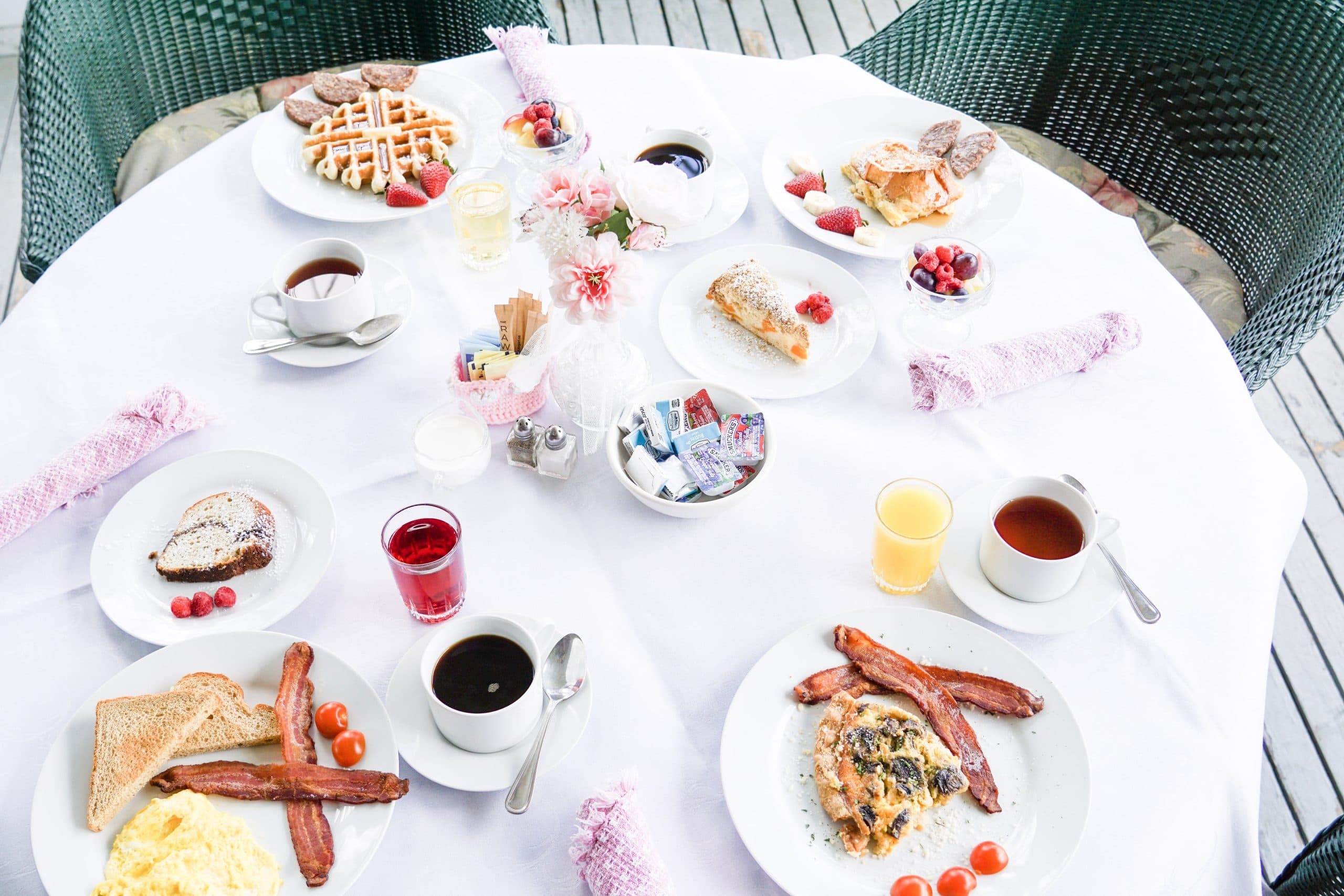 A beautifully arranged breakfast spread featuring various dishes, coffee, and juices on a white tablecloth.
