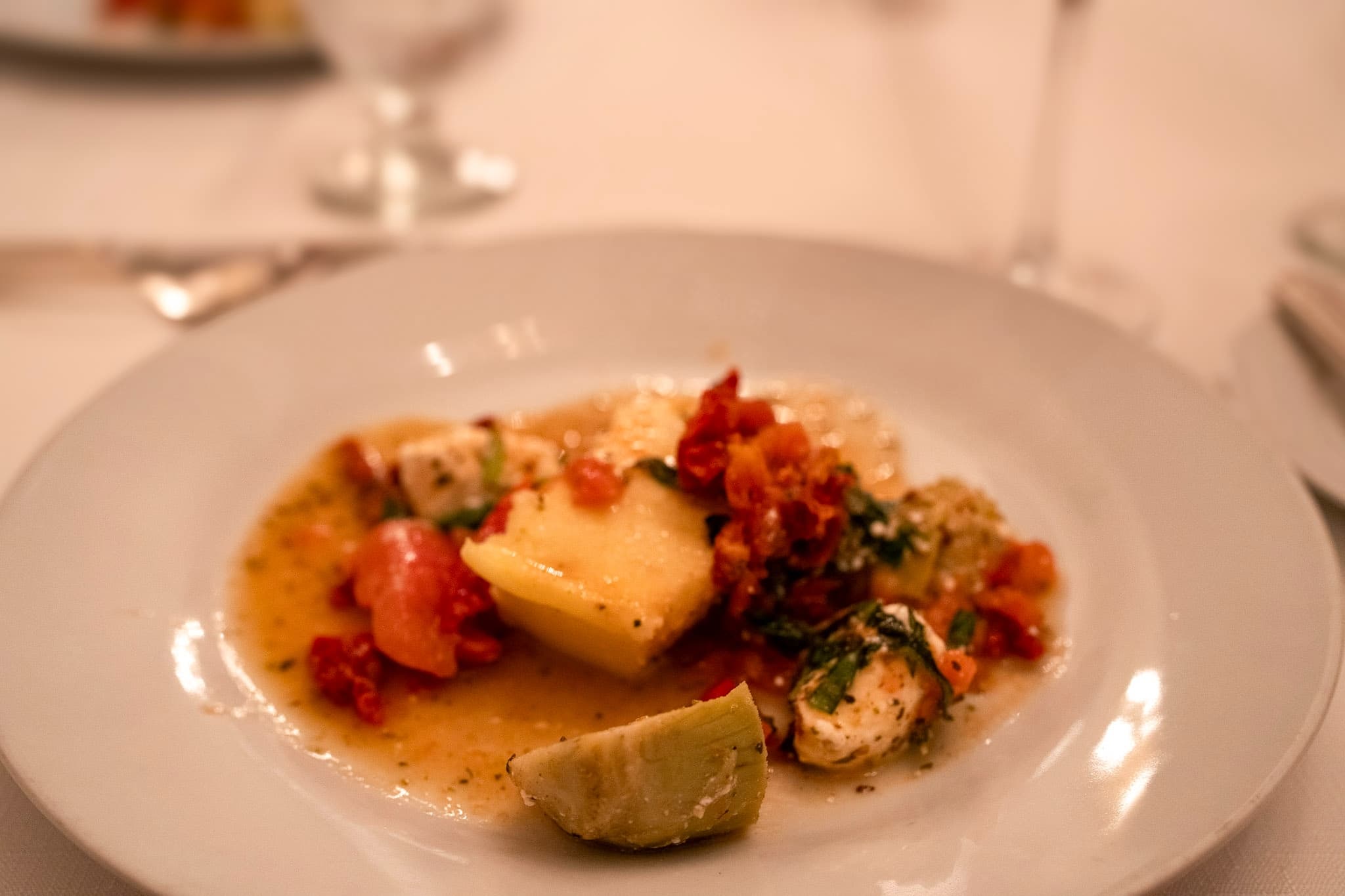 A plate of seafood and potatoes garnished with herbs and lime.
