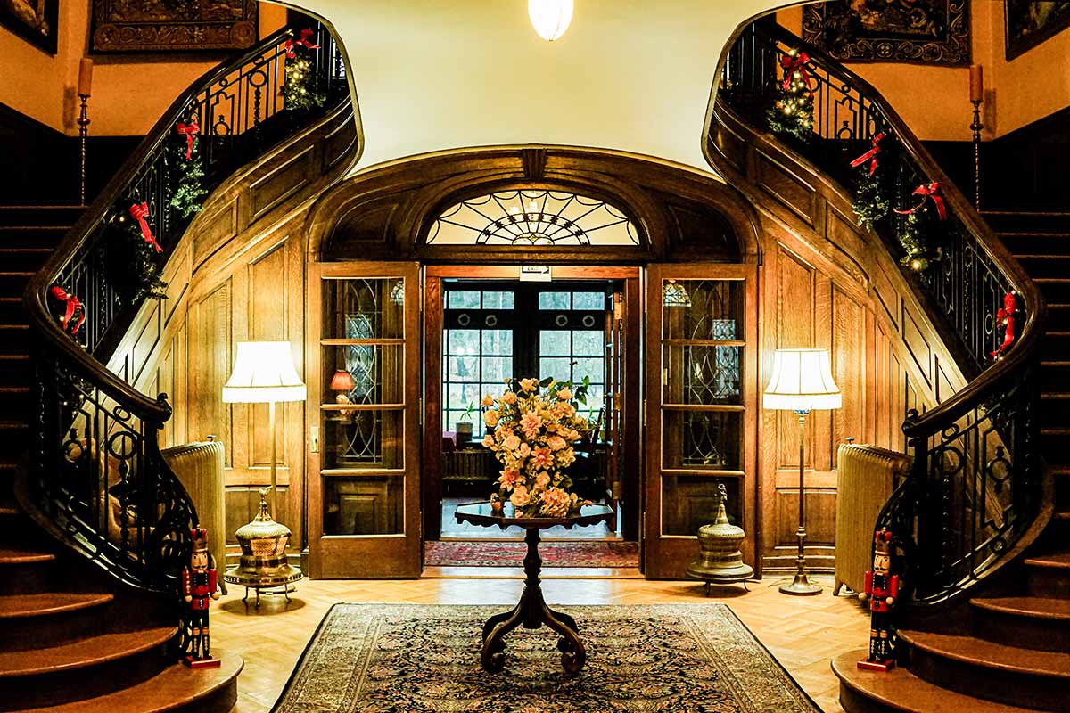 Elegant entryway featuring a grand staircase, decorative flowers, and warm lighting.