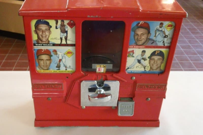 A vintage red vending machine displaying baseball cards featuring players' images.