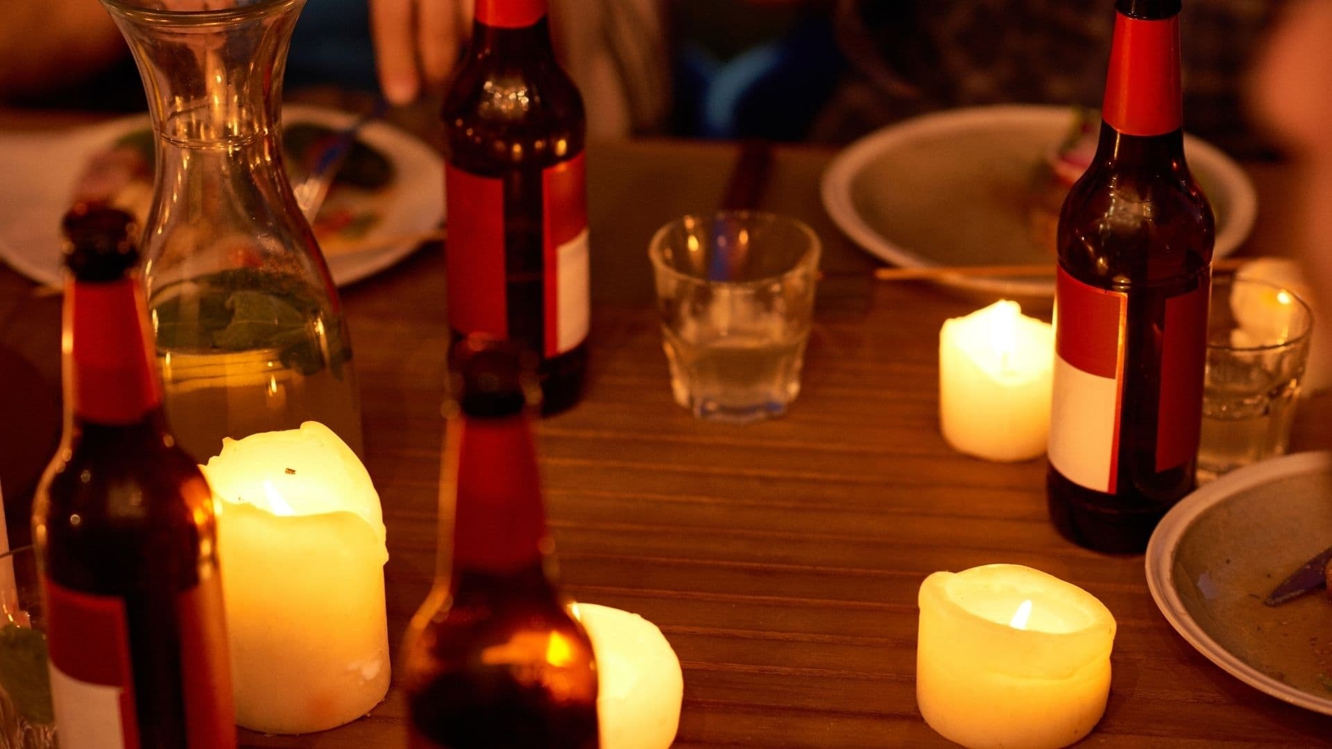 A table set with beer bottles and illuminated candles in a cozy atmosphere.