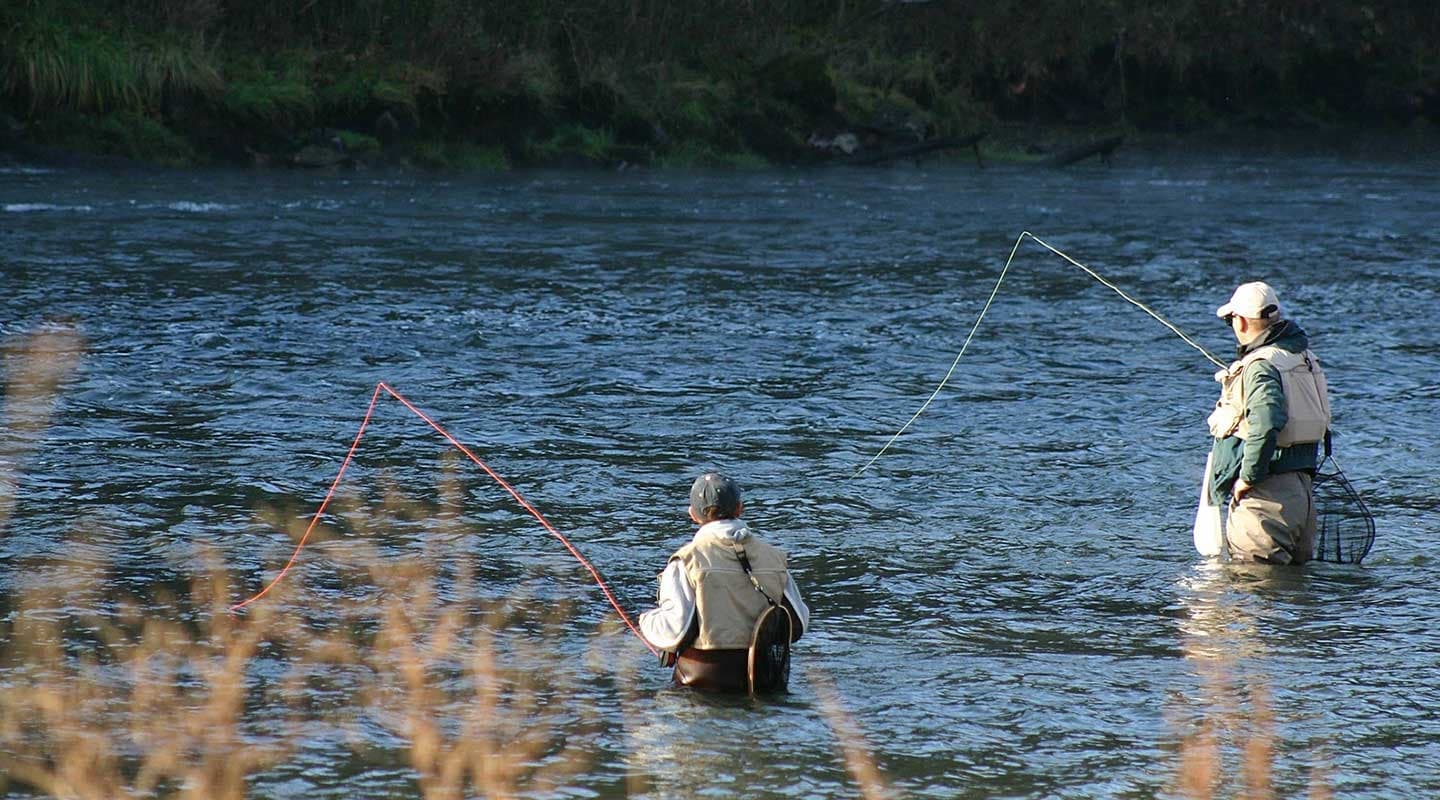 Two anglers fishing in a river.