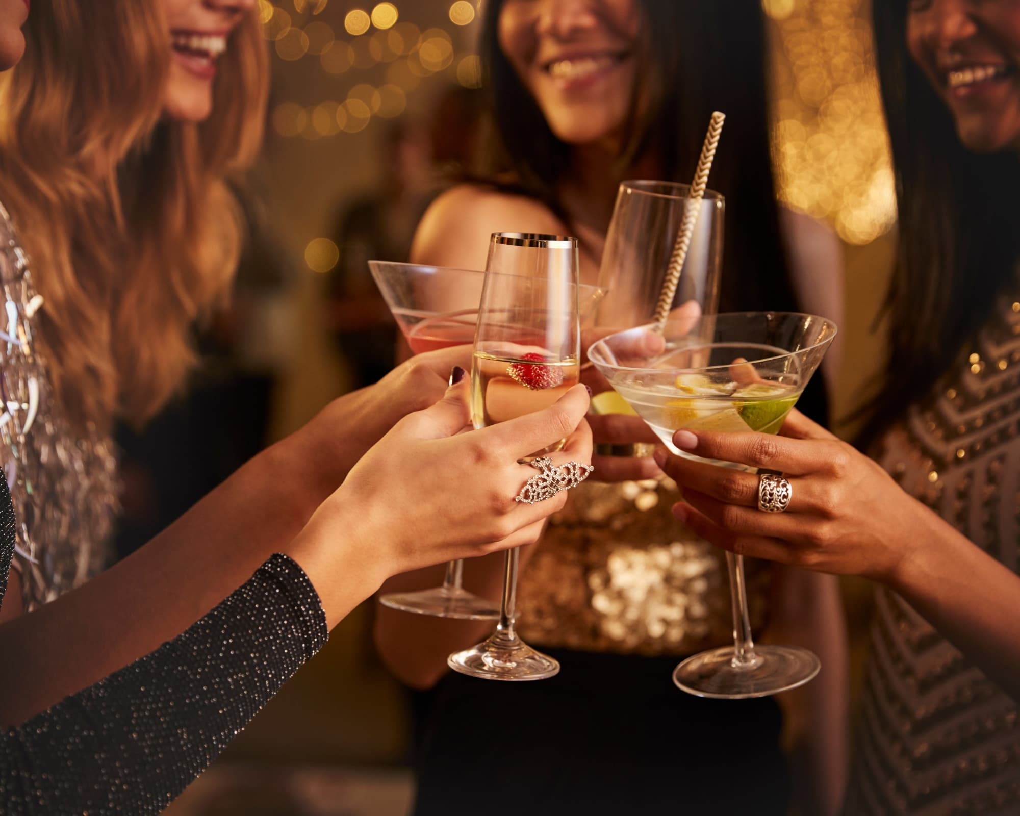 A group of friends joyfully clinking their cocktail glasses together at a celebration.