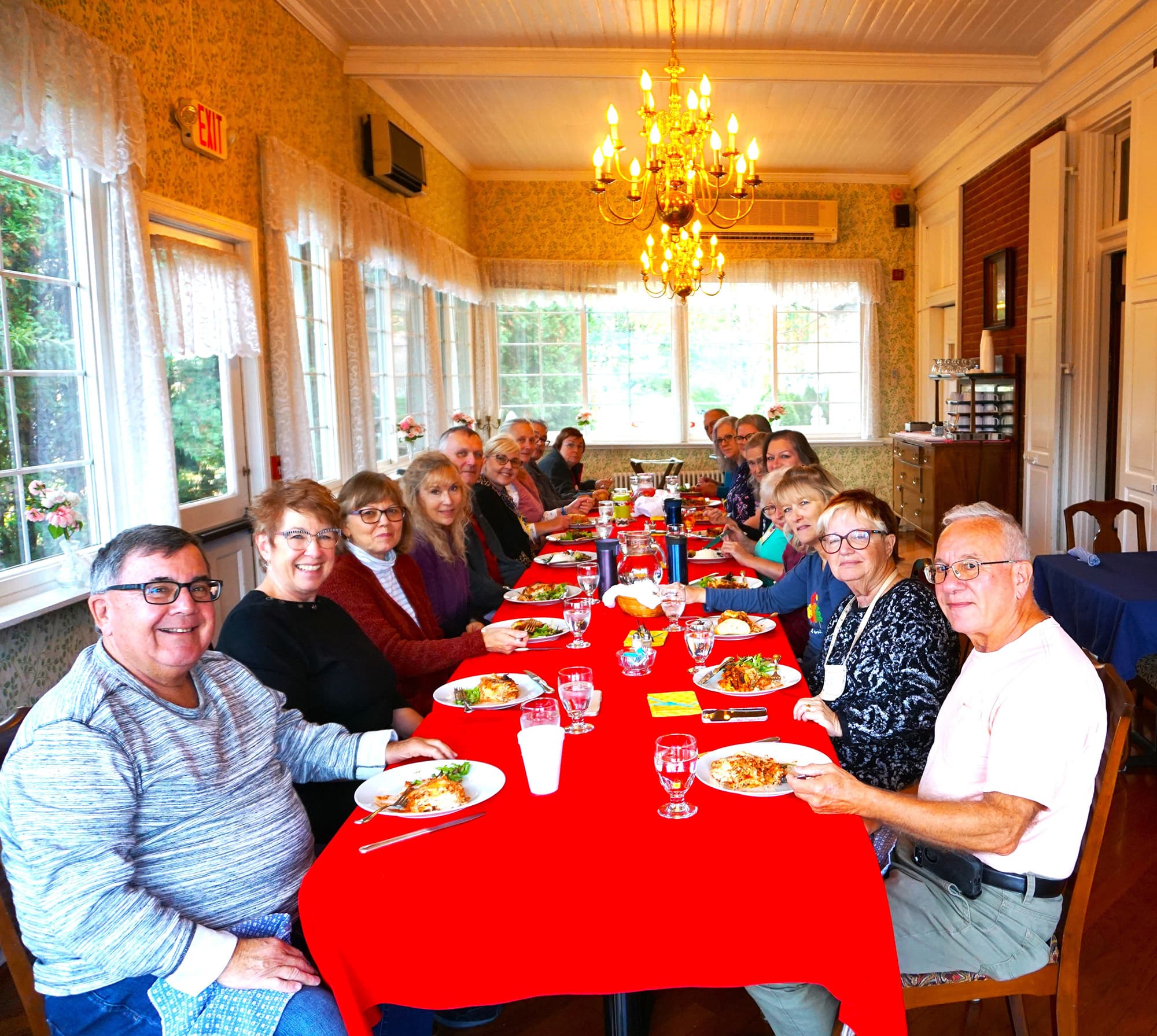 A group of people enjoying a meal together at a long table in a cozy dining room.