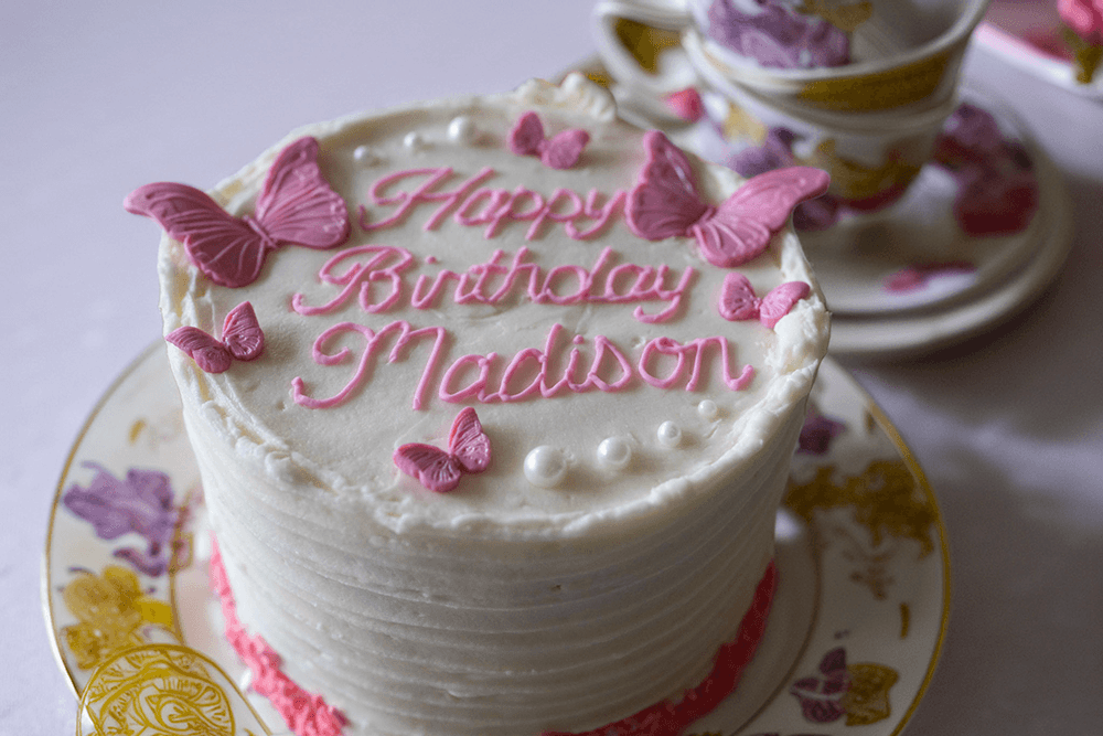 A birthday cake topped with pink frosting and butterflies, inscribed with "Happy Birthday Madison."