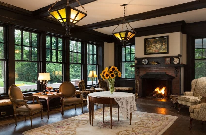 Cozy living room featuring large windows, a fireplace, and a vase of sunflowers on a table.