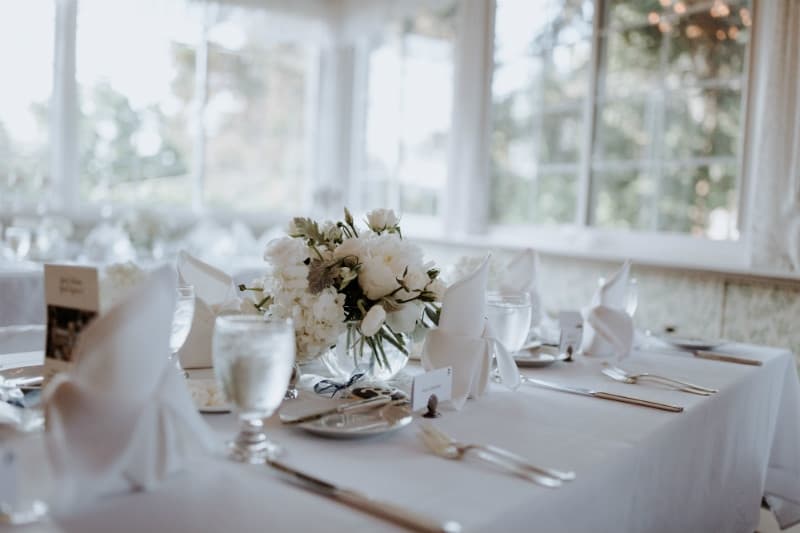 A beautifully set dining table with a floral centerpiece, glassware, and folded napkins.