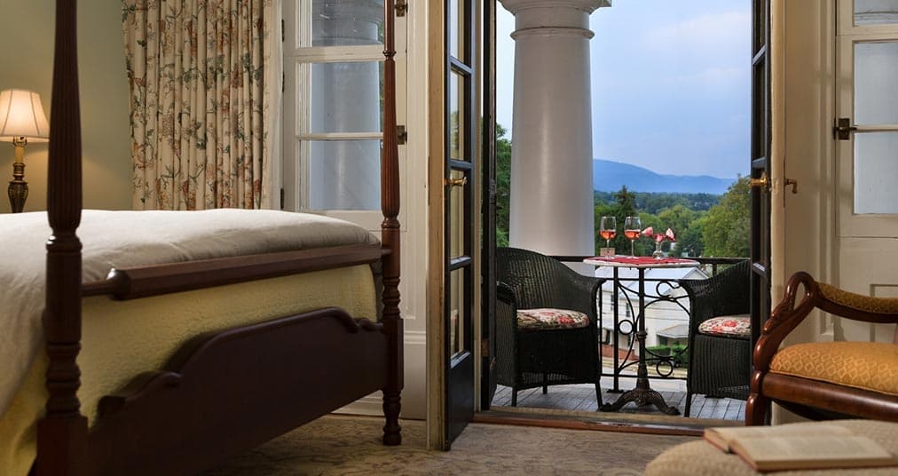 A cozy bedroom with an open balcony overlooking a scenic view.