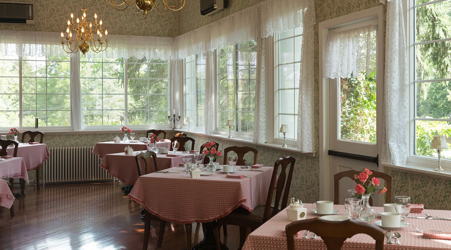 A bright, elegant restaurant with checkered tables, fresh flowers, and large windows.