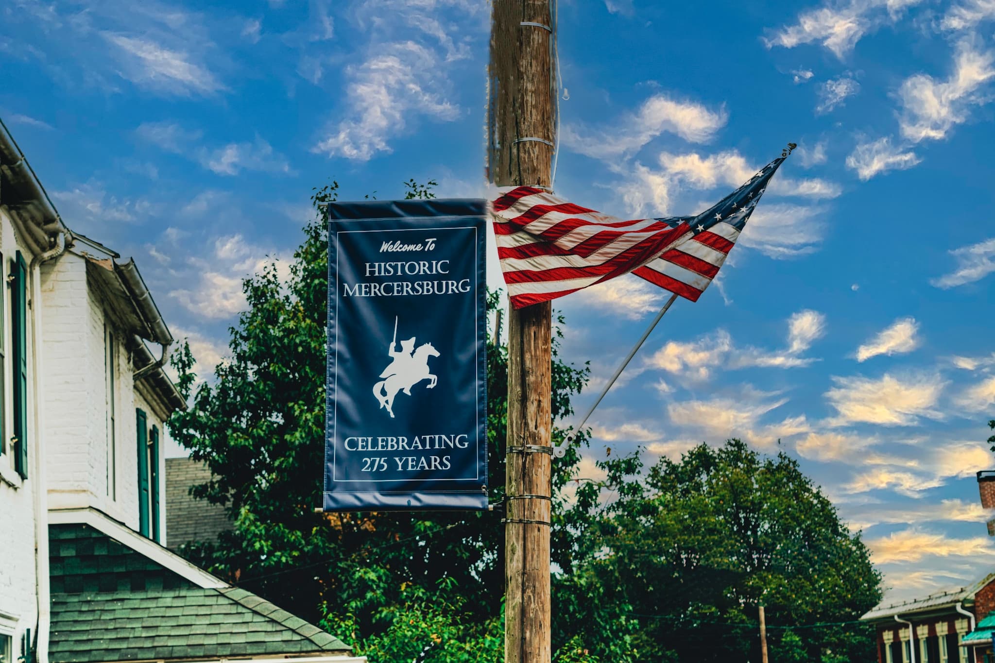 A banner welcoming visitors to Historic Mercersburg, celebrating 275 years, alongside a waving American flag.