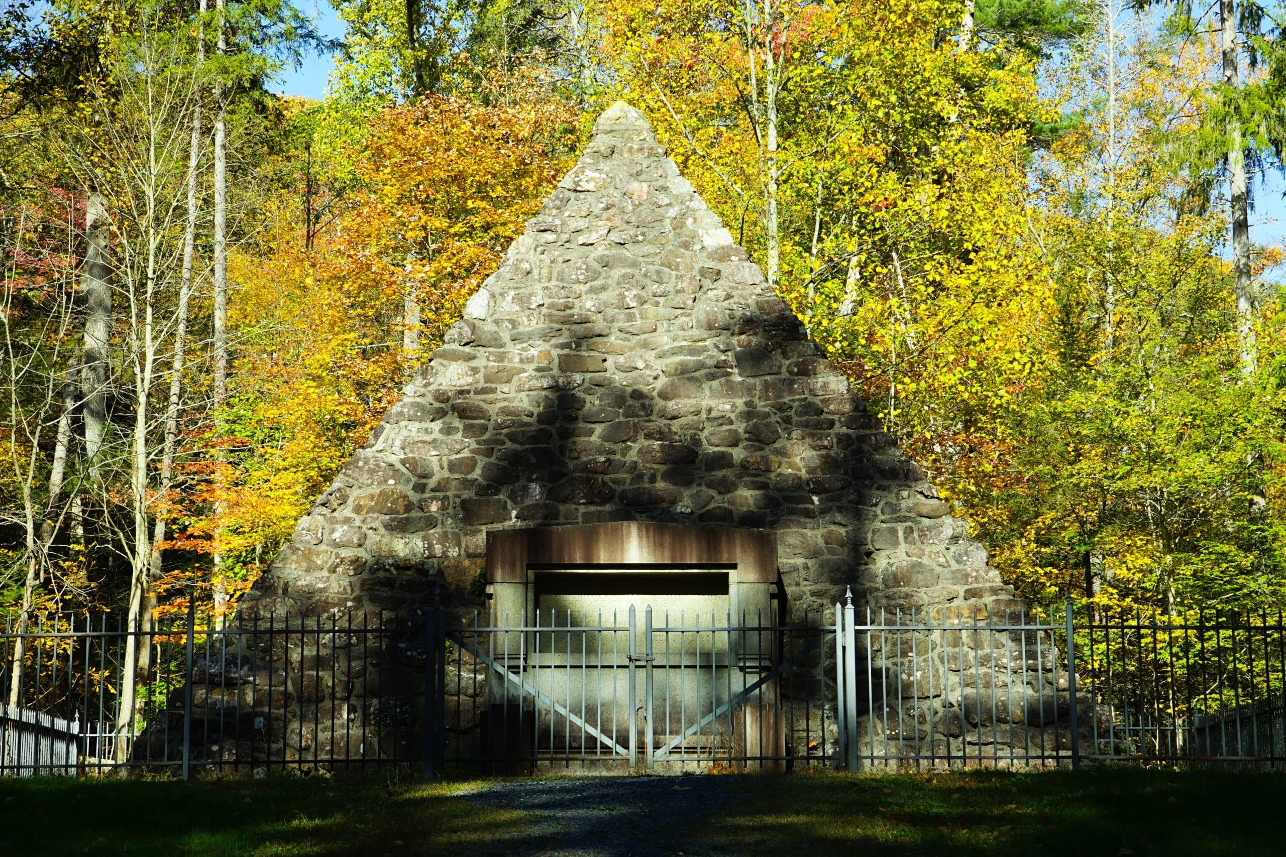 A stone pyramid-shaped building surrounded by colorful autumn foliage.