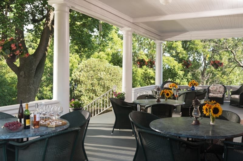 A serene outdoor patio with tables adorned with sunflowers, wine, and glasses, surrounded by lush greenery.