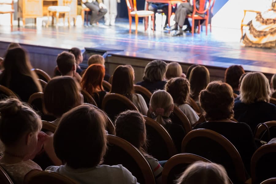 A crowd of people sitting in an audience watching a performance on stage.