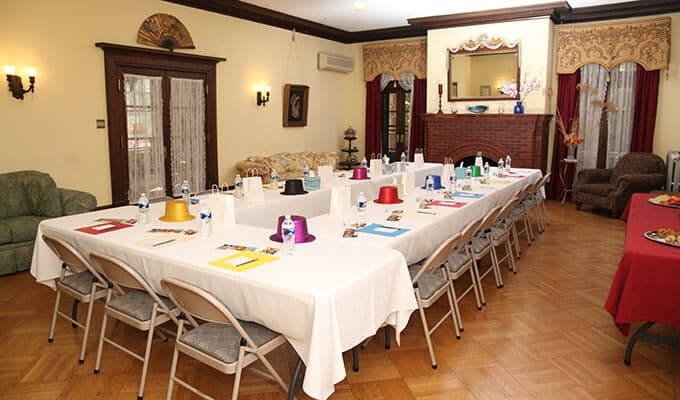 A spacious meeting room set up with a long table, chairs, and colorful place settings.