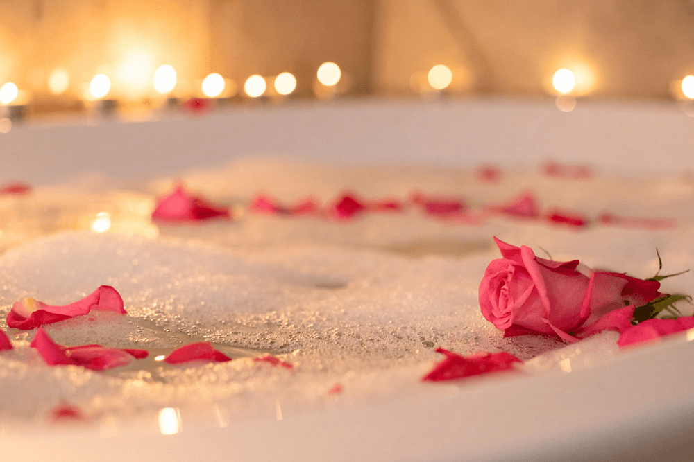 A luxurious bubble bath with rose petals and soft candlelight.