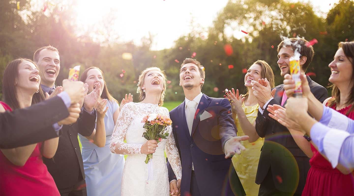 A joyful wedding scene with a bride and groom in the center, surrounded by smiling friends celebrating outdoors. Petals are tossed in the air, creating a festive atmosphere. A joyful wedding scene with a bride and groom in the center, surrounded by smiling friends celebrating outdoors. Petals are tossed in the air, creating a festive atmosphere.