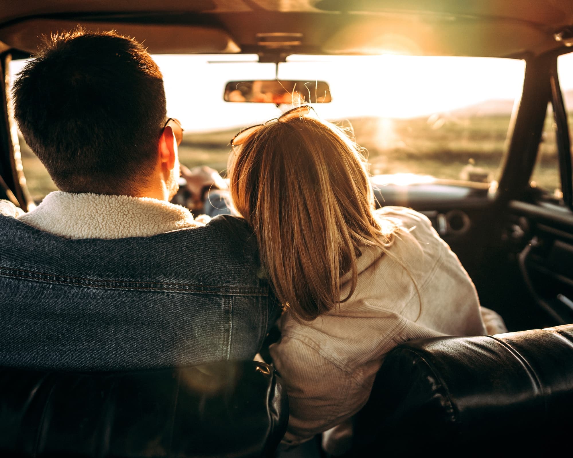 A couple sits in a car at sunset, the woman resting her head on the man's shoulder. Warm sunlight filters through the window, creating a cozy, intimate atmosphere. A couple sits in a car at sunset, the woman resting her head on the man's shoulder. Warm sunlight filters through the window, creating a cozy, intimate atmosphere.