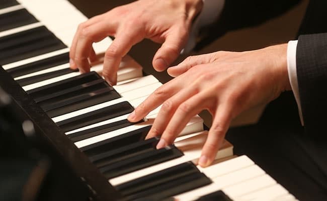 Hands gracefully playing a piano, showcasing fingers on black and white keys. The scene conveys a sense of skill and musical passion. Hands gracefully playing a piano, showcasing fingers on black and white keys. The scene conveys a sense of skill and musical passion.